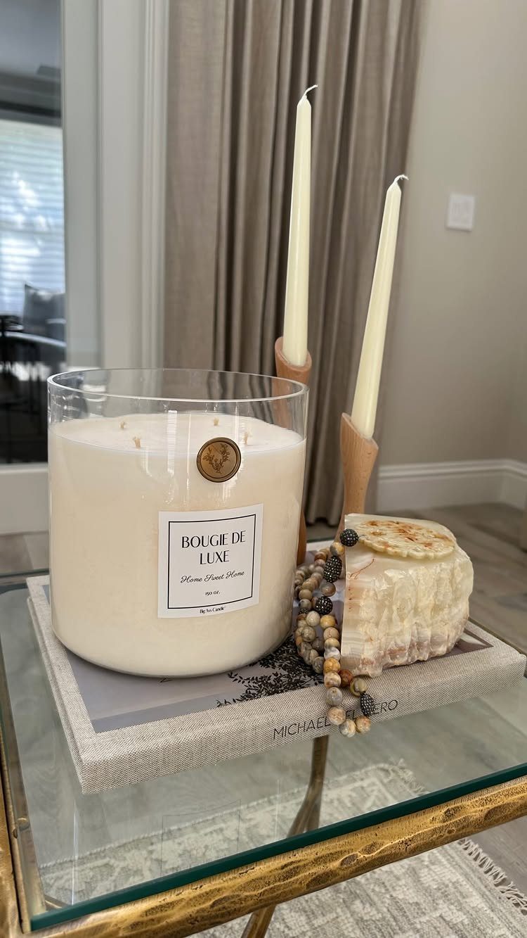 White luxury scented candle and taper candles arranged on a glass coffee table