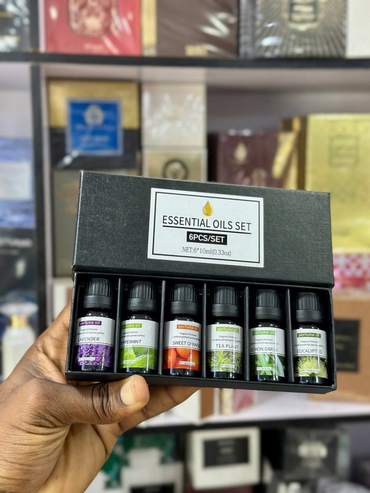 Essential oils set in a black box held by a person's hand.