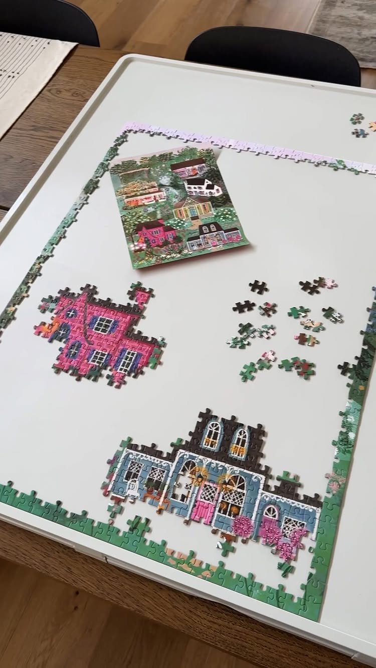 Partially completed jigsaw puzzle of colorful houses on a white puzzle board