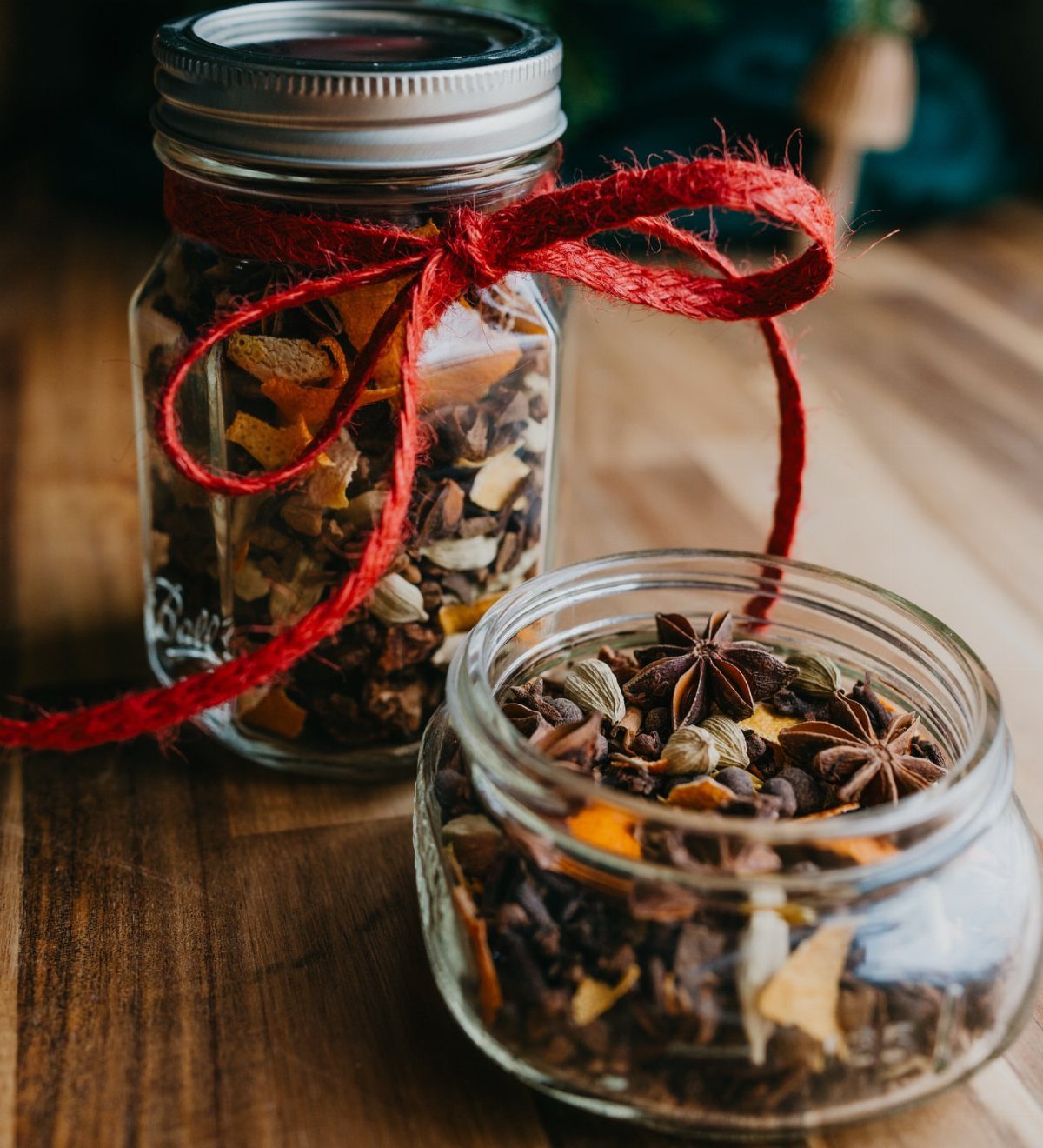 Two glass jars filled with mulling spices and star anise on wooden table