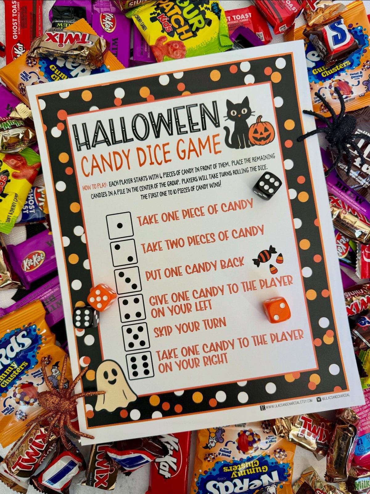 Halloween Candy Dice Game instruction sheet surrounded by colorful candies and plastic spiders.