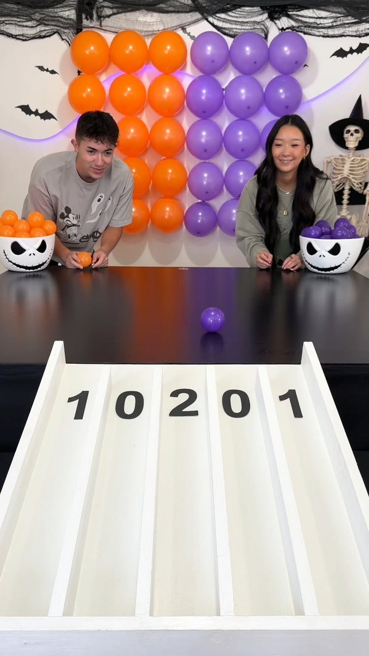 Two people playing a ball game with orange and purple balloon decorations.