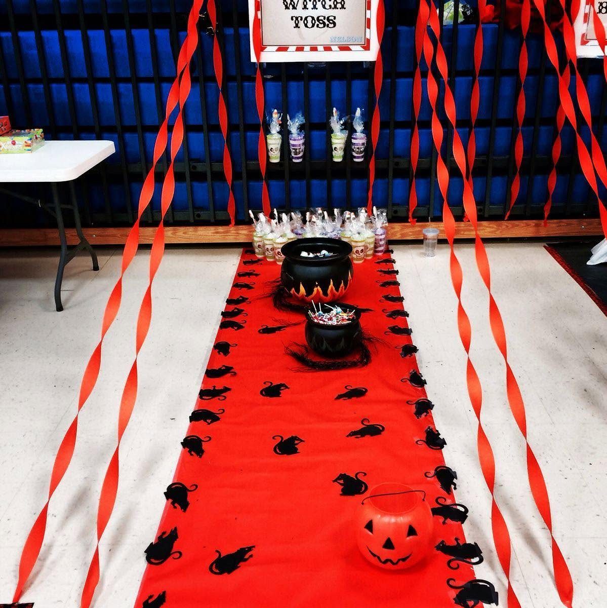 Halloween party setup with red runner, black cauldrons, and Witch Toss sign.
