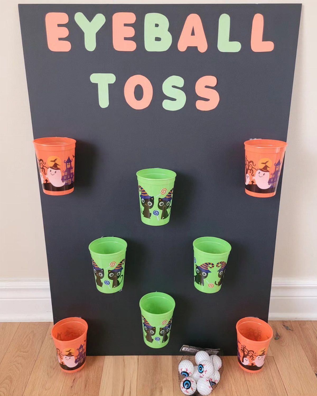 Eyeball toss game with colorful plastic cups on a black board and plush eyeballs.