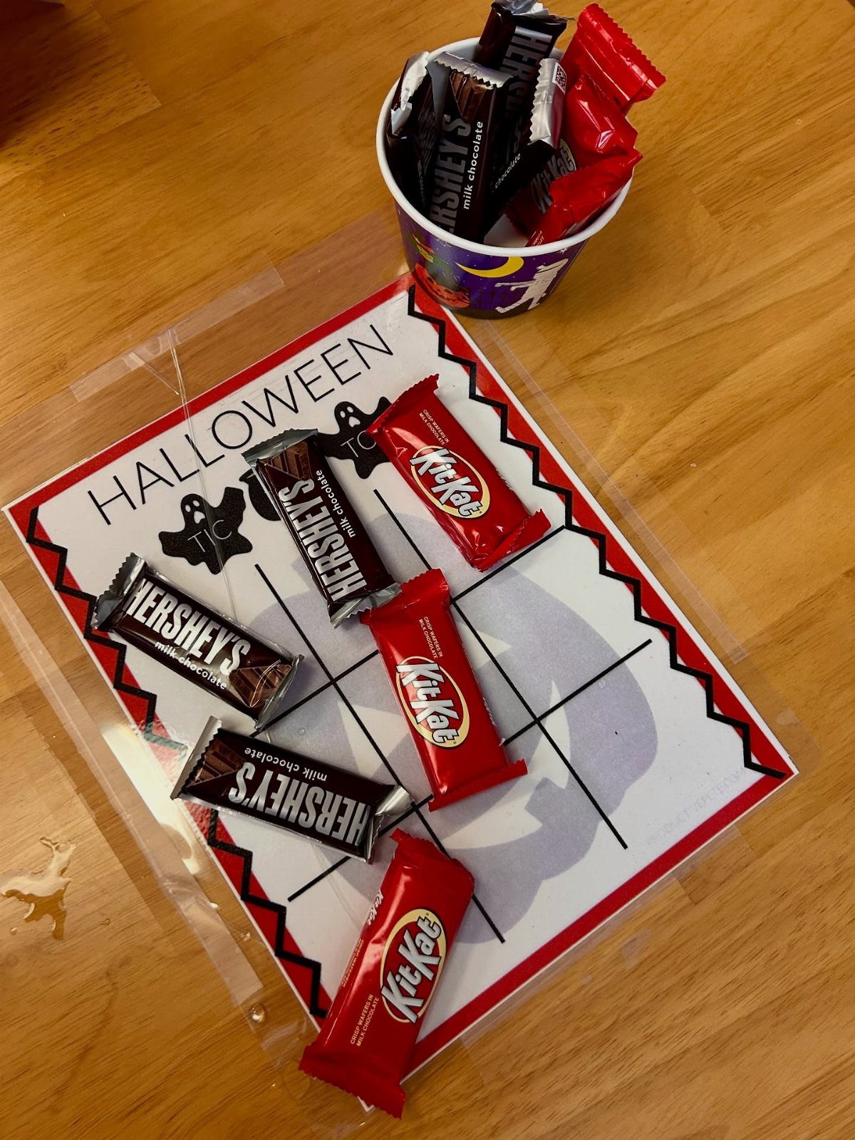Halloween tic-tac-toe game board using chocolate bars as pieces on a wooden table