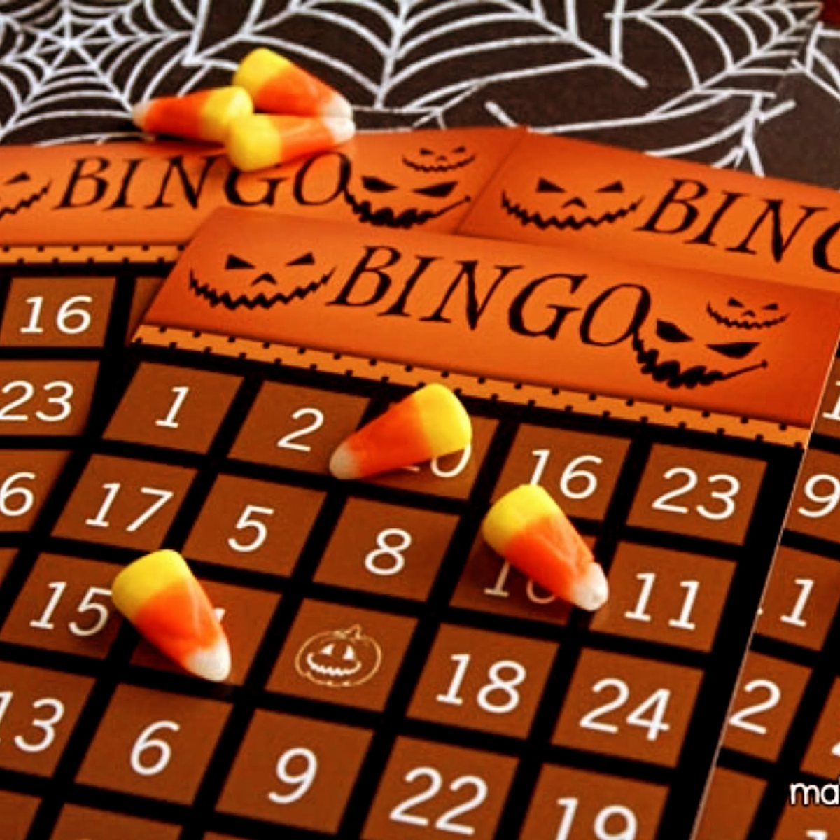 Halloween bingo cards with candy corn markers on a spiderweb background