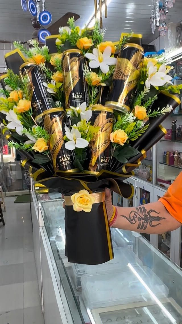 Beer bouquet with black and gold cans, yellow and white flowers, wrapped in black.