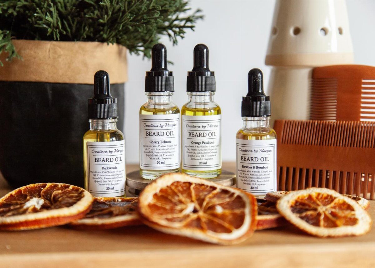 Four bottles of beard oil with dried orange slices and a wooden comb.