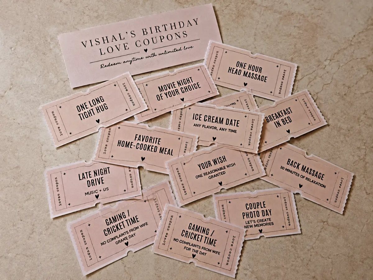 Handmade pink love coupons for a birthday gift scattered on a stone surface.