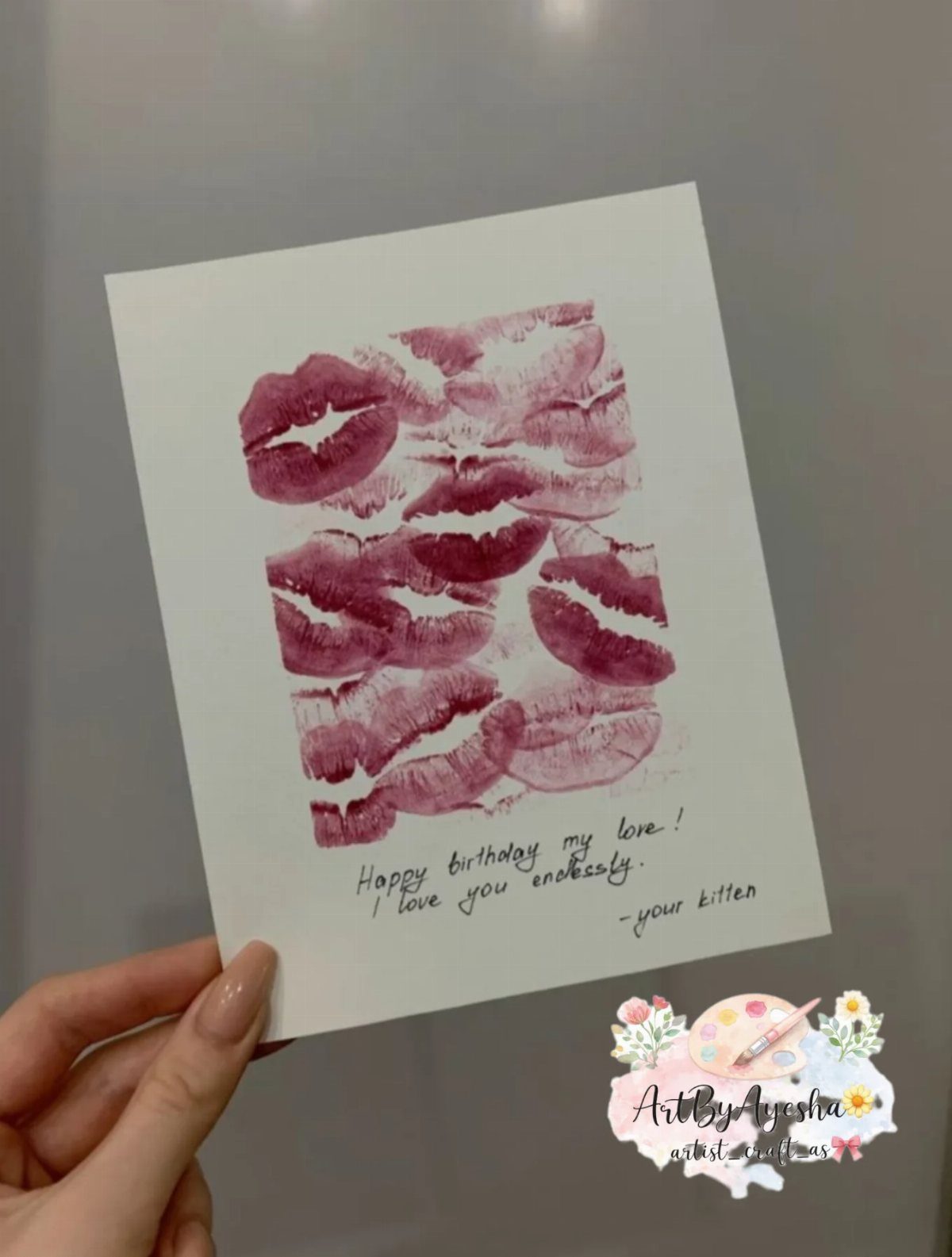 White paper with red lipstick kiss prints and a handwritten birthday love note.