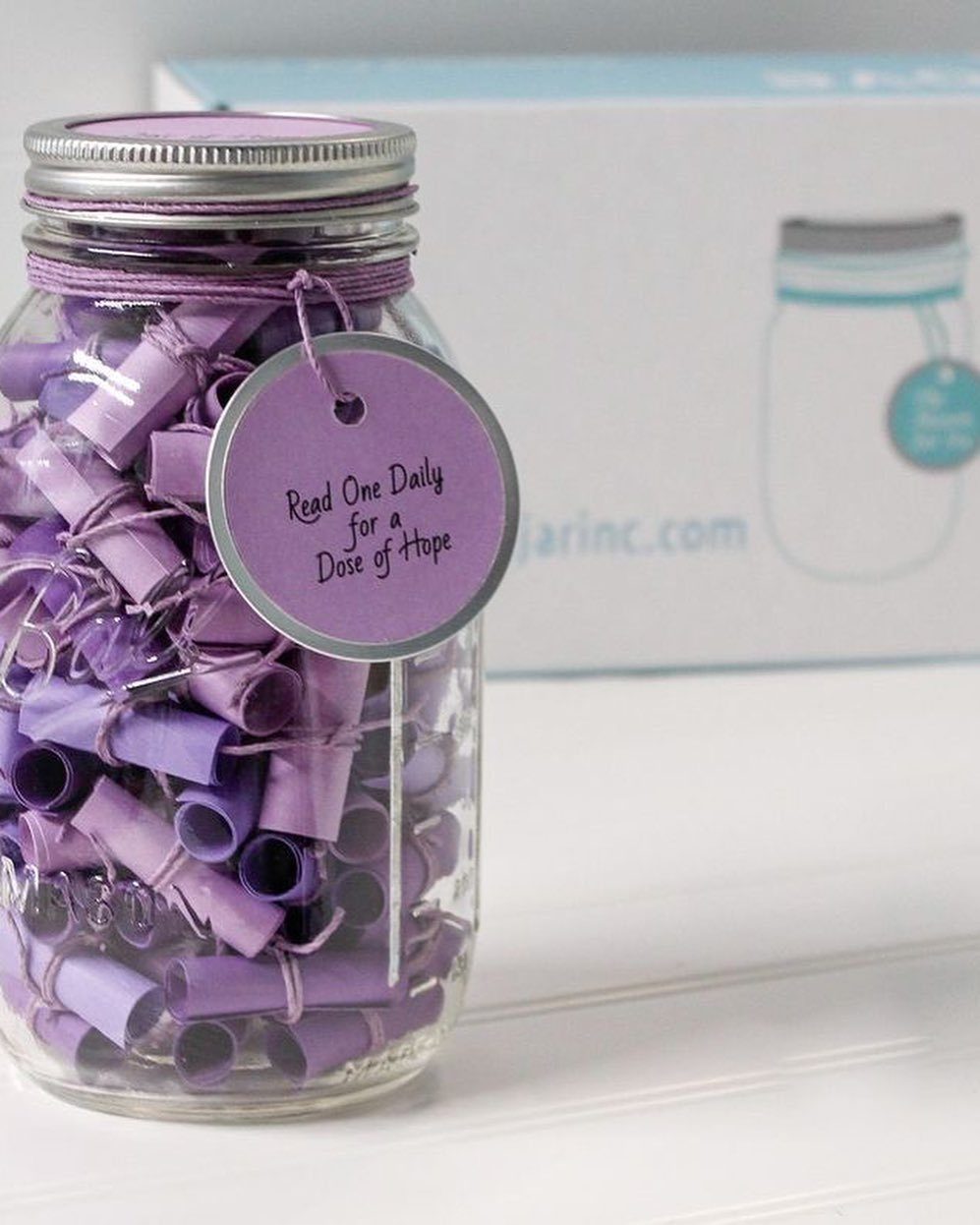Glass jar filled with purple rolled paper scrolls and a hope tag.