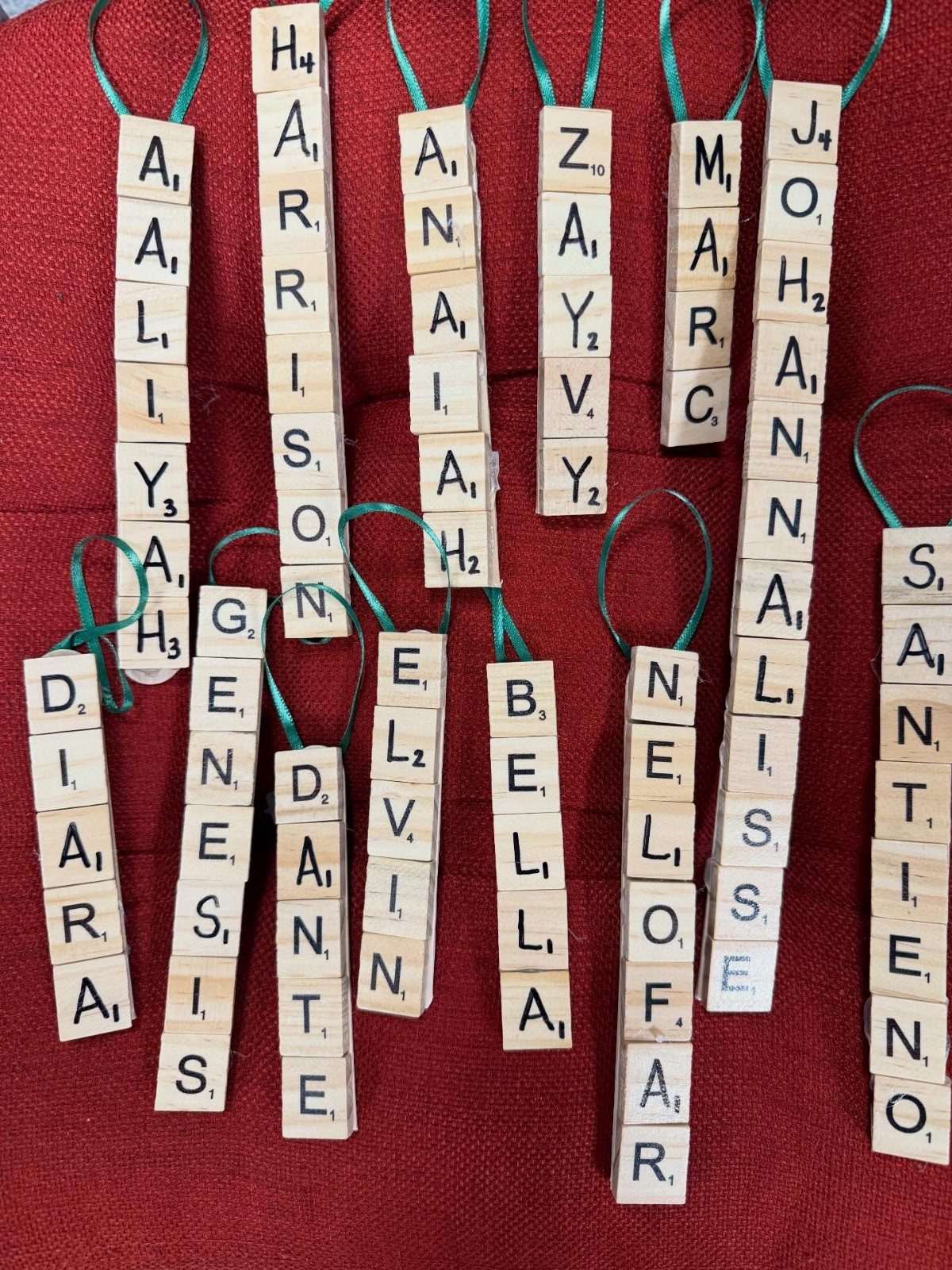 Wooden Scrabble tile name tags with green ribbons on a red background