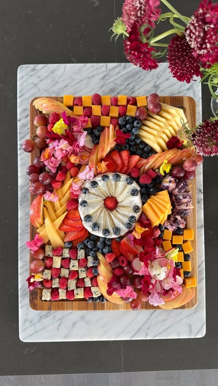 Brie cheese wheel topped with berries centered on a colorful fruit and cheese board.