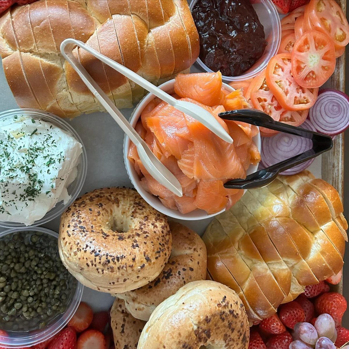 Challah bread, smoked salmon, bagels, and fresh fruit arranged on a large platter.