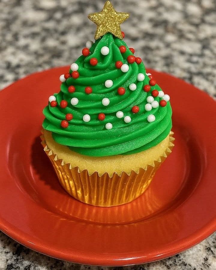 Christmas tree cupcake with green frosting, red and white sprinkles, and gold star.