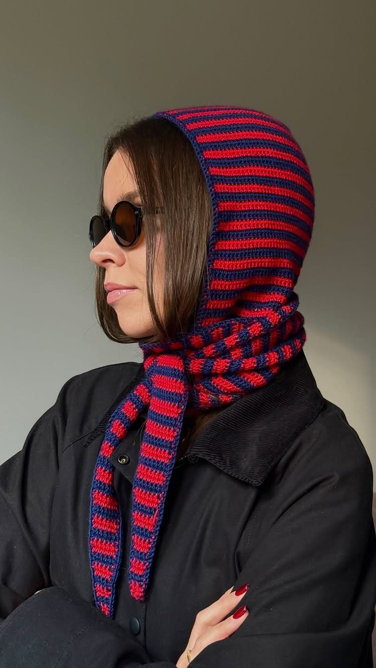 Woman wearing a red and navy blue striped crochet hood and matching scarf.
