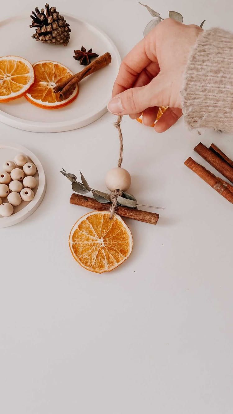 Hand holding a DIY Christmas ornament made of dried orange and cinnamon.