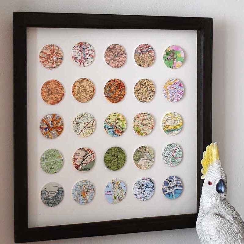 Framed art featuring a grid of colorful circular map cutouts on white background