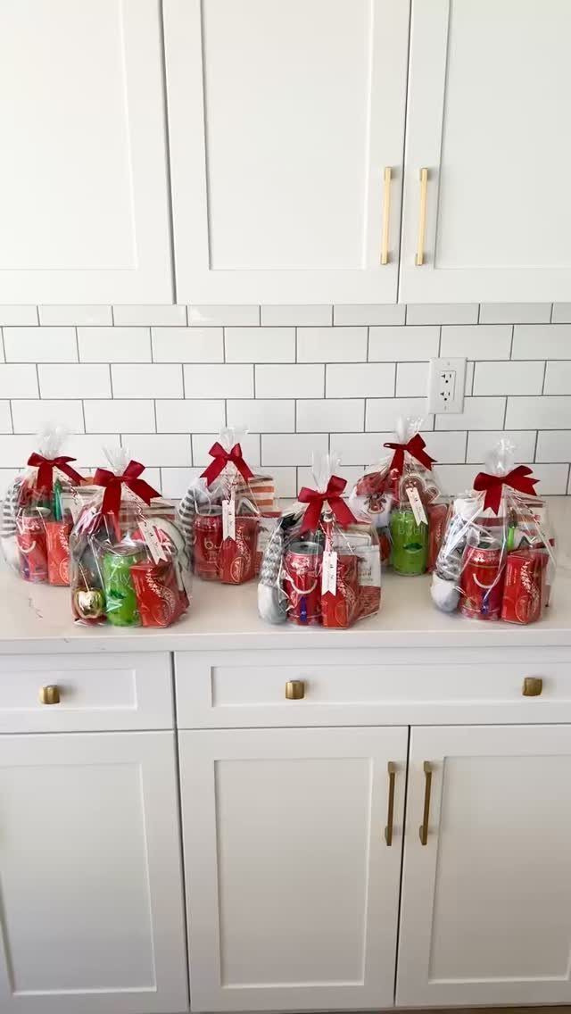 Clear cellophane gift bags with red ribbons filled with holiday treats on a counter