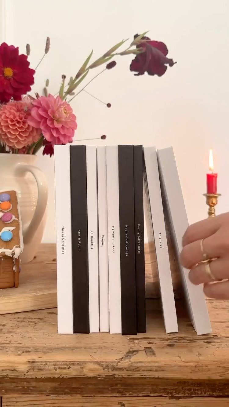 White and black hardcover photo books standing on a rustic wooden table.