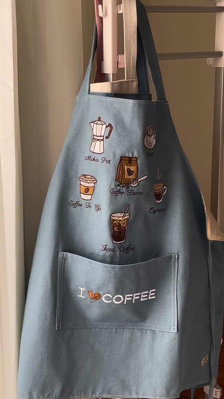 Light blue apron with embroidered coffee illustrations and I LOVE COFFEE text on pocket