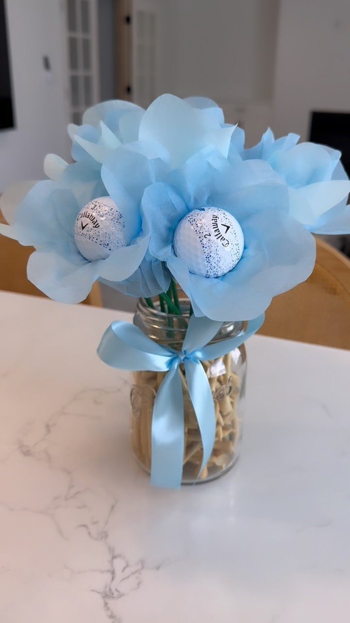 Blue tissue paper flowers in a glass jar tied with a blue ribbon.