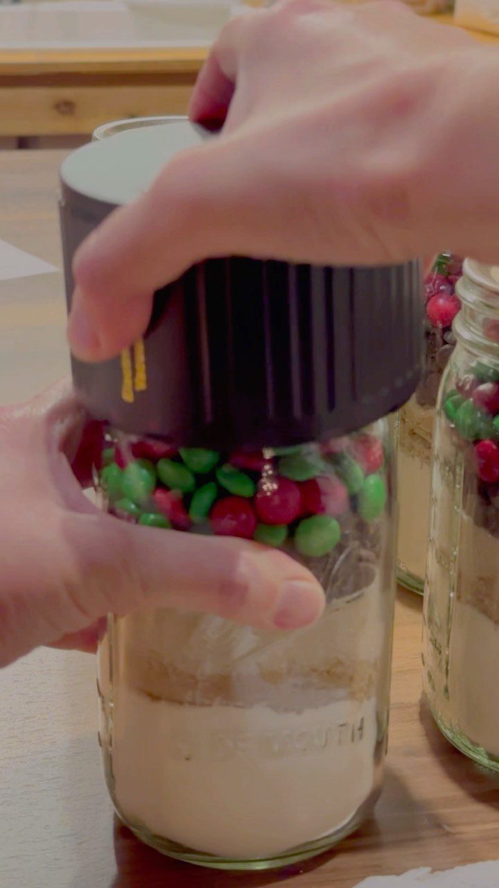 Mason jar filled with layered cookie mix and red and green candies.