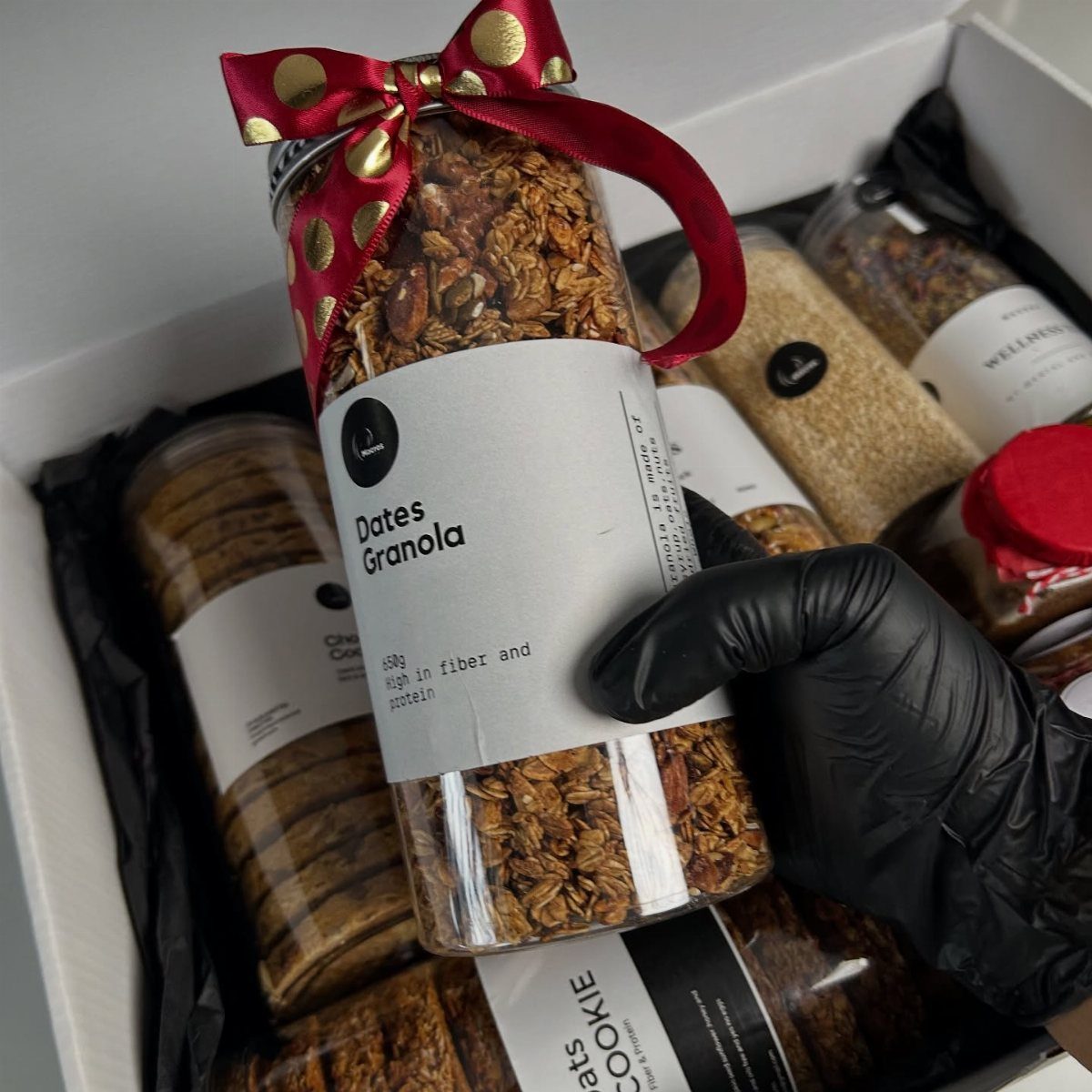 Mason jar filled with granola and a red polka-dot ribbon in a gift box