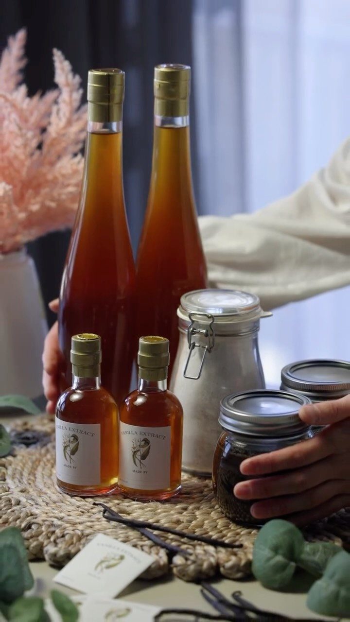 Amber vanilla extract in glass bottles and jars with vanilla pods on a mat