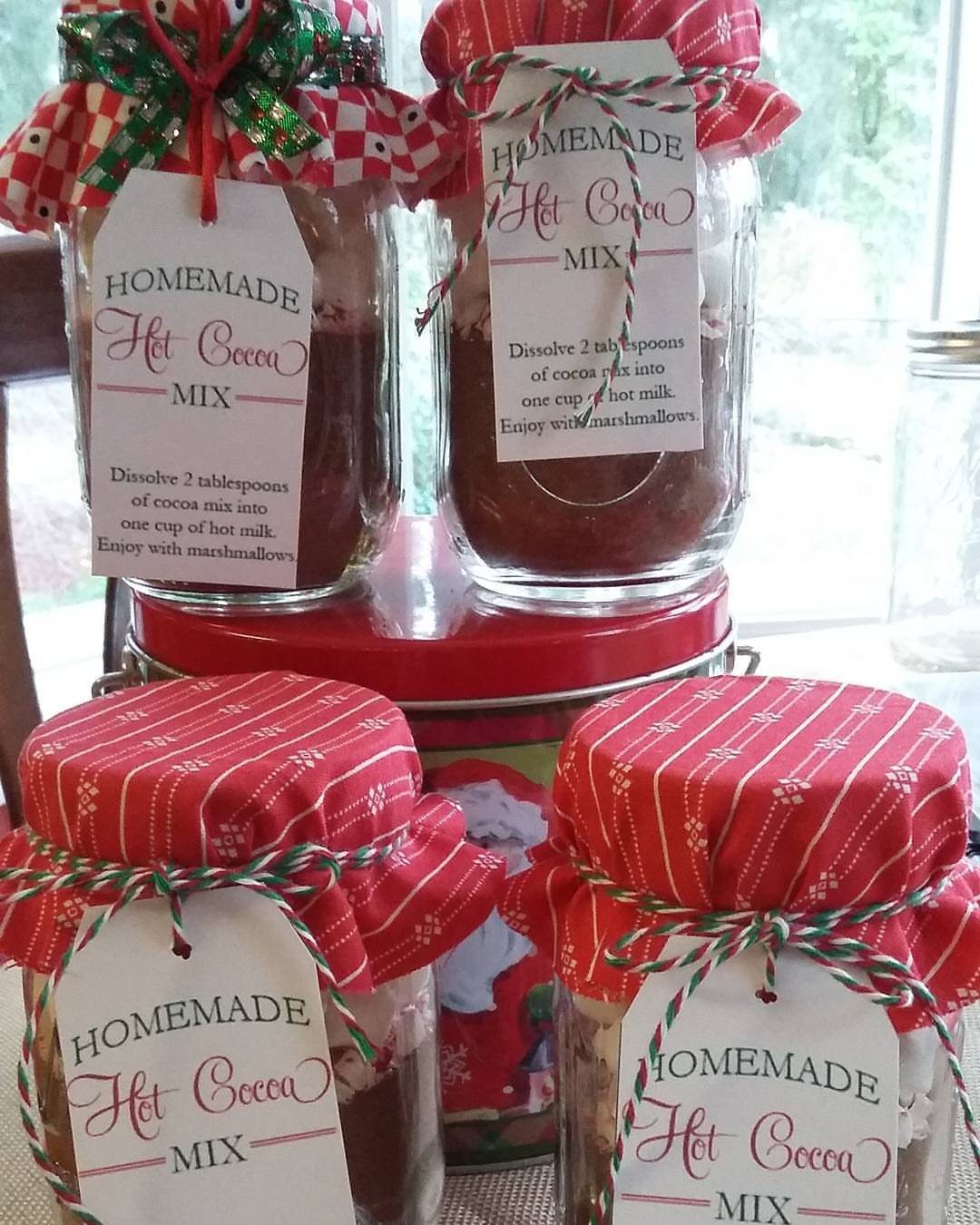Mason jars filled with hot cocoa mix, topped with red fabric and gift tags.