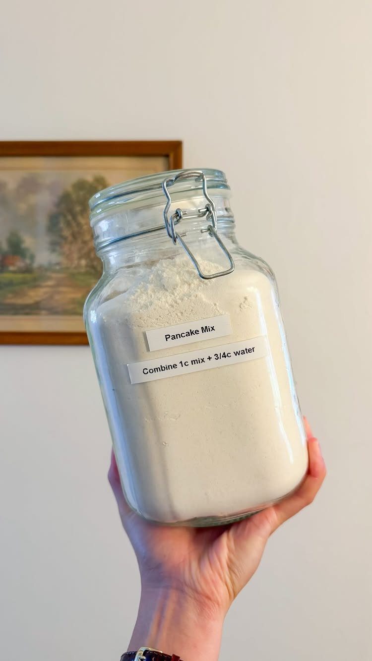 Glass mason jar filled with pancake mix held by a person's hand.