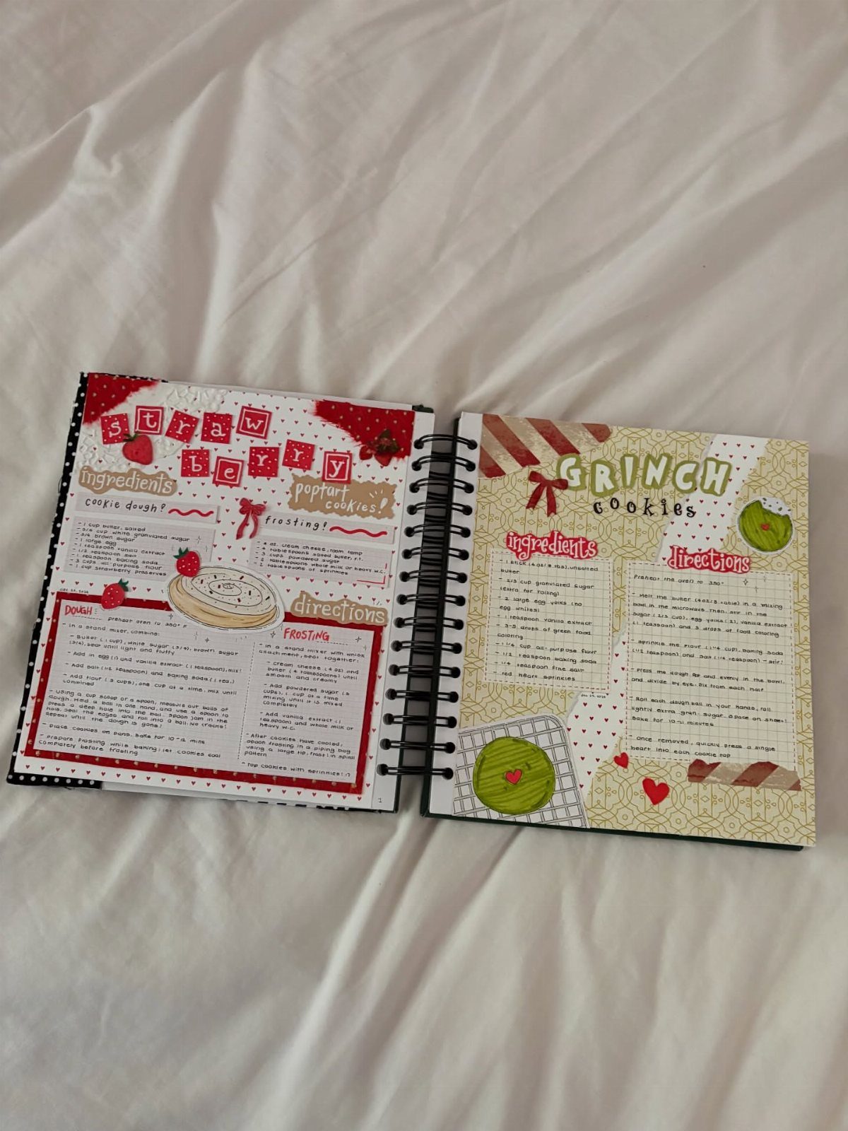 Open spiral recipe book with colorful handwritten holiday cookie recipes on white fabric