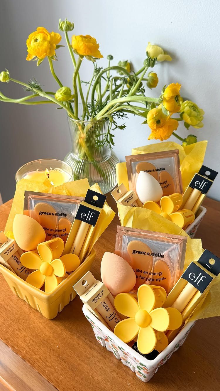 Three small gift baskets filled with yellow makeup products and yellow flowers.