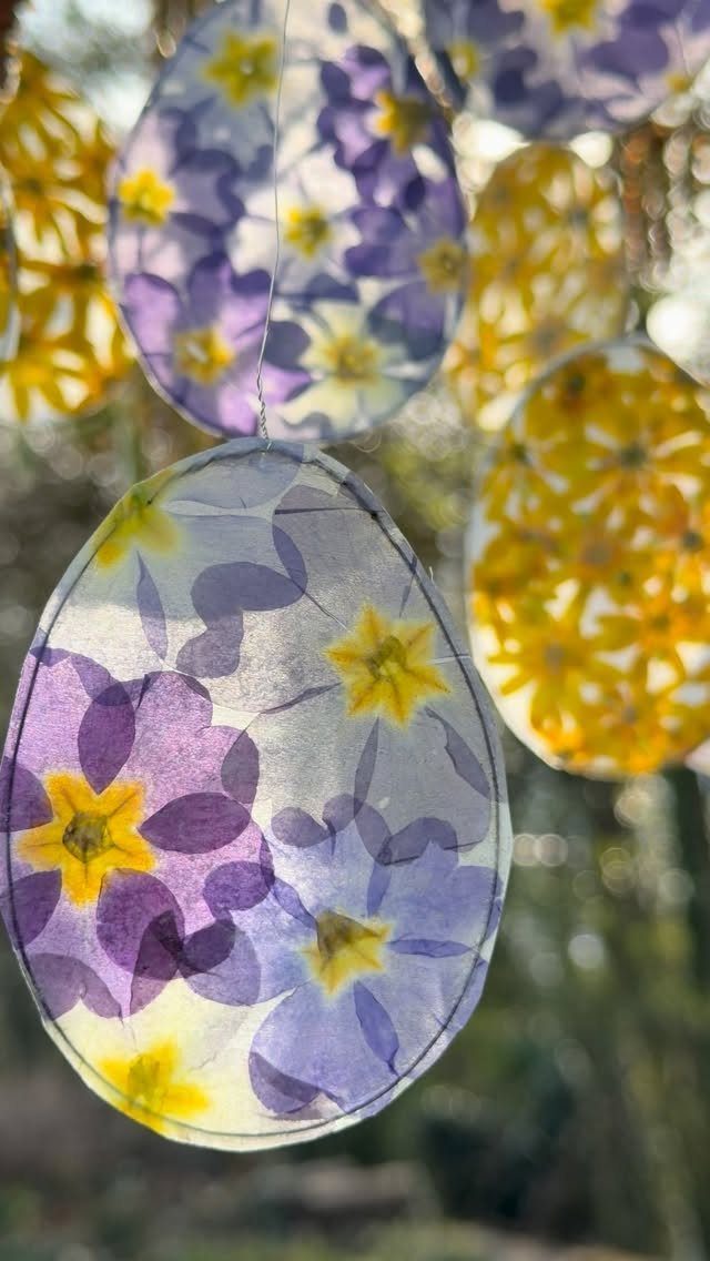 Oval translucent plastic sheets with pressed purple and yellow flowers hanging outdoors.