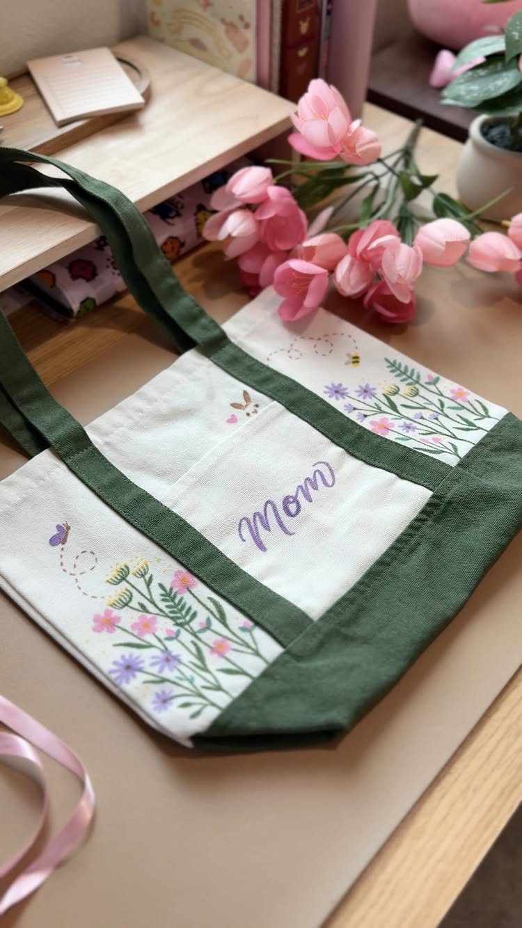 Embroidered white and green tote bag with 'Mom' text and floral patterns.