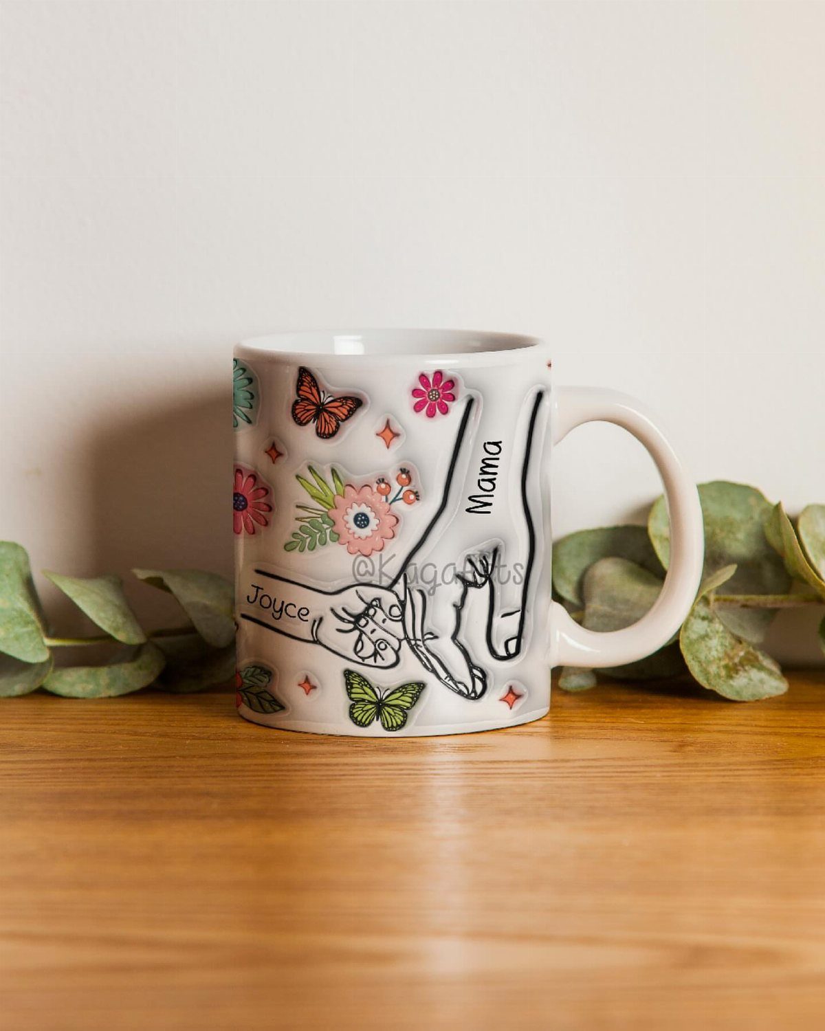 White ceramic mug with hand illustrations, butterflies, and flowers on a wooden table.