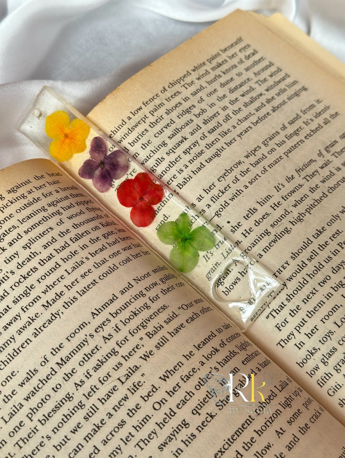Resin bookmark with colorful pressed flowers resting on an open book page