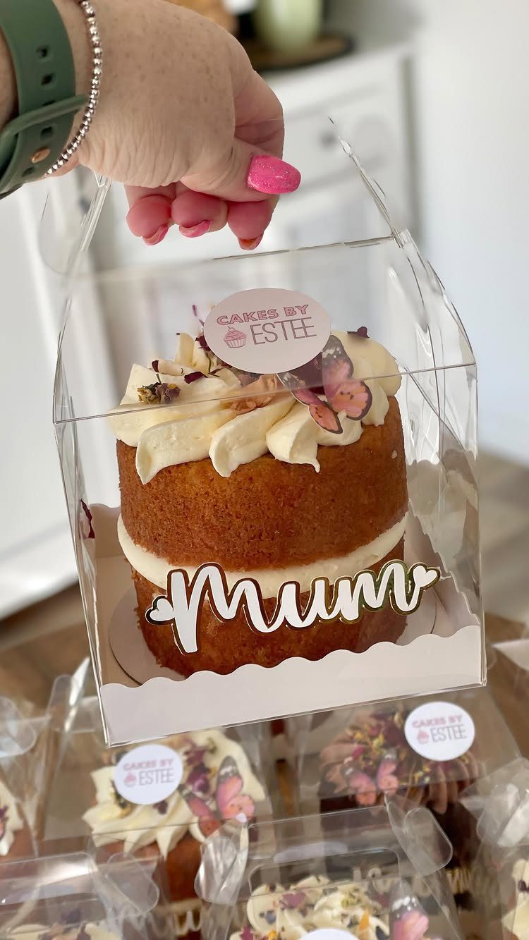 Small layered cake with white frosting and Mum topper in clear packaging