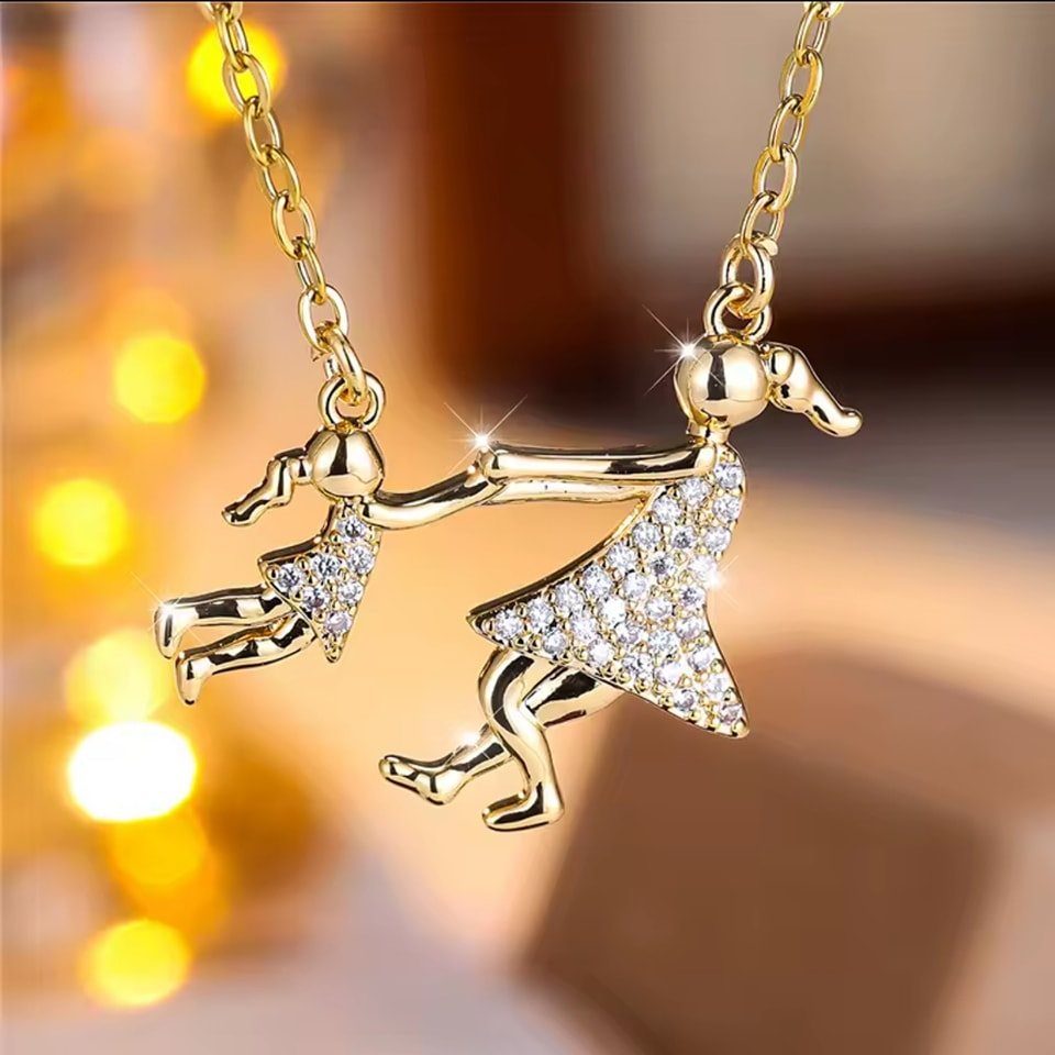 Gold necklace with two figures holding hands, featuring crystal-embellished dresses.