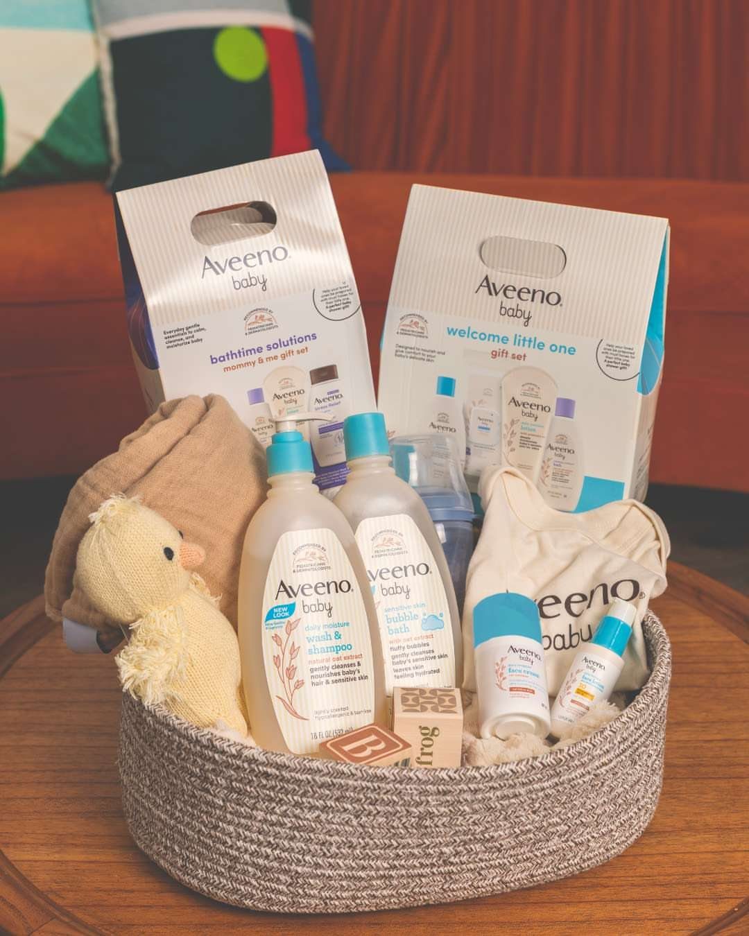 Woven basket filled with Aveeno Baby skincare products and a plush duck toy.