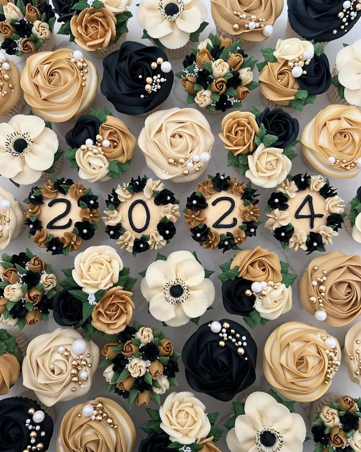 Cupcakes decorated with gold and black frosting, including four spelling out 2024.