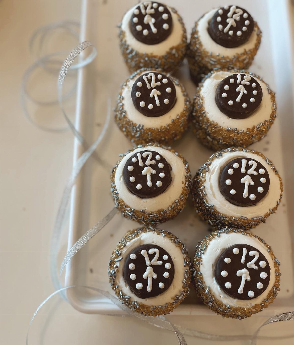 Cupcakes with clock face chocolate toppers and gold and silver sprinkles on tray
