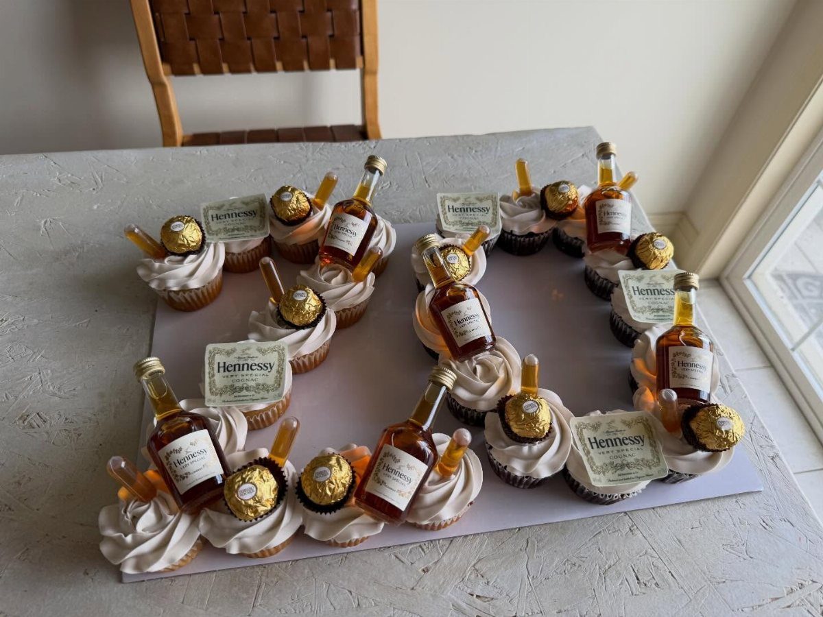 Cupcakes with white frosting and miniature liquor bottles forming the number 2020.