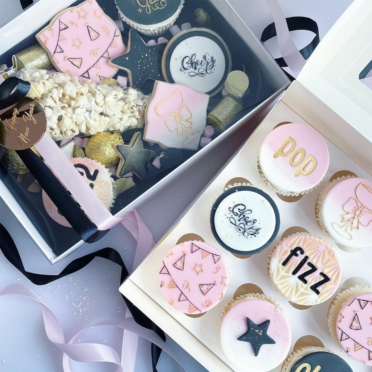 New Year's Eve cupcakes and cookies in white gift boxes with festive decorations.