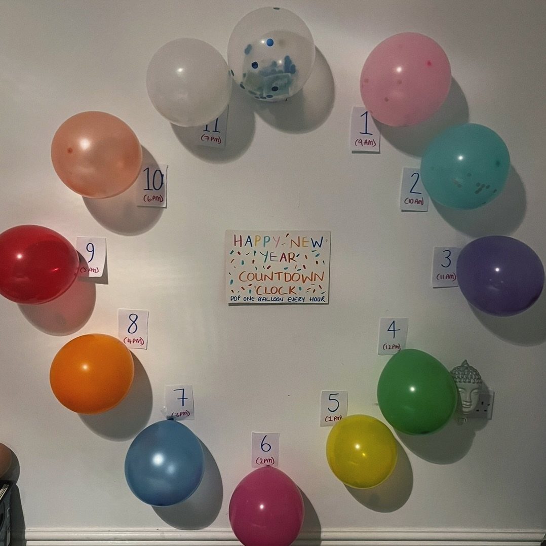 Colorful balloons arranged like a clock on a wall for a New Year countdown.