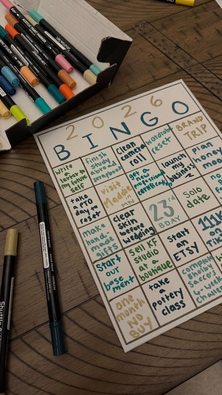 Hand-drawn 2026 bingo card with goal ideas and colorful markers on wood.