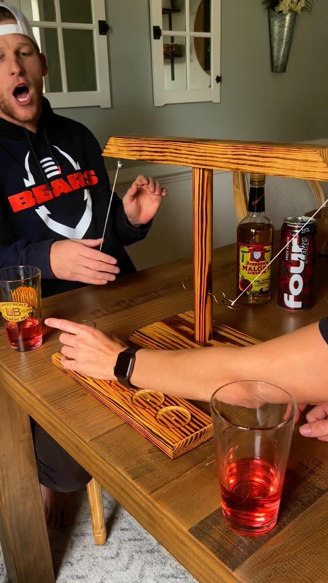 Man reacting to a wooden tabletop drinking game with liquor and drinks.