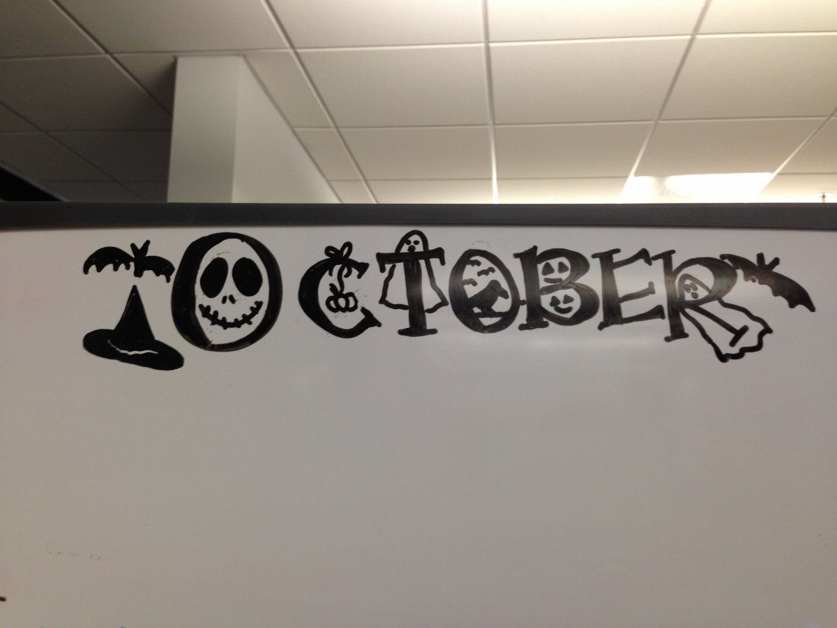Halloween themed October lettering drawn in black marker on a white board
