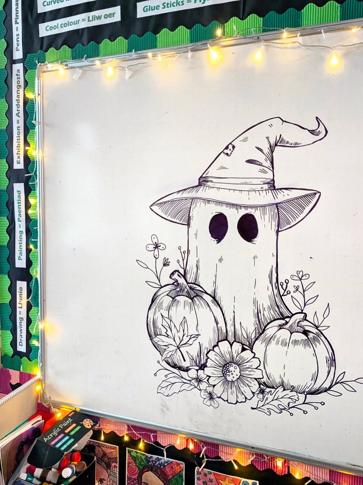 Ghost wearing a witch hat with pumpkins drawn in black ink on a whiteboard