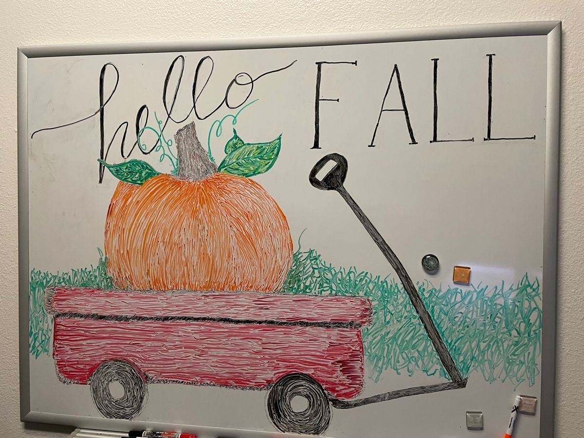 Whiteboard drawing of a pumpkin in a red wagon with Hello Fall text.